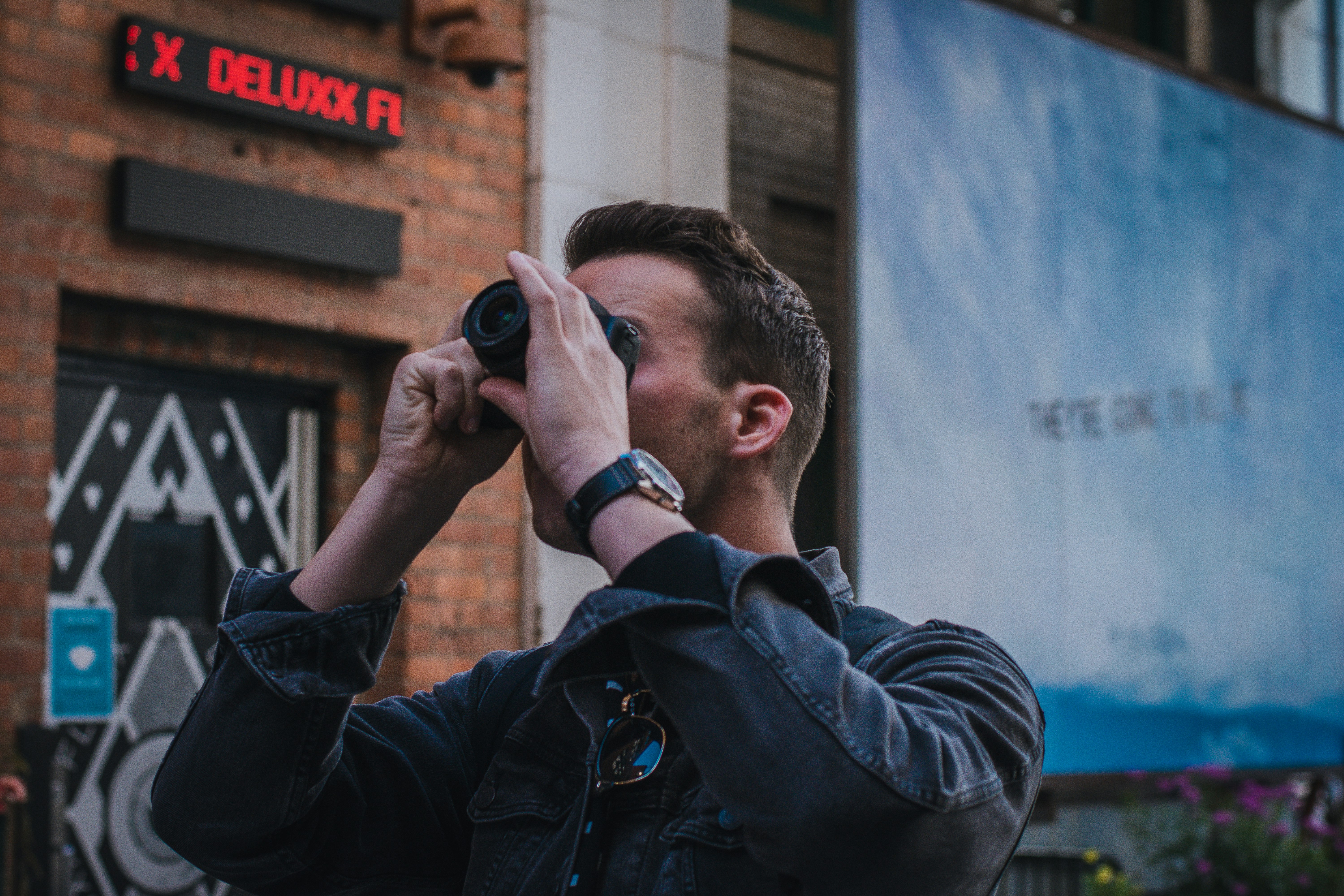 man in black leather jacket holding black camera